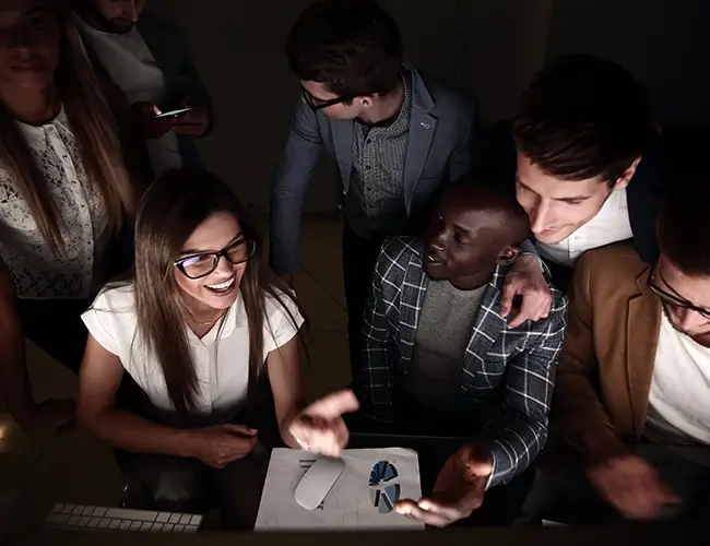 Group of people sat around a table smiling in the dark